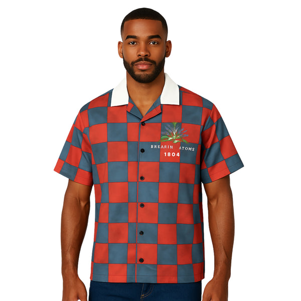 Model wearing Breakin' Atoms "Liberation 1804 Button-Up," a short sleeve shirt honoring the Haitian Revolution, featuring rich blue, red, and black tones and cultural motifs symbolizing freedom and resistance.