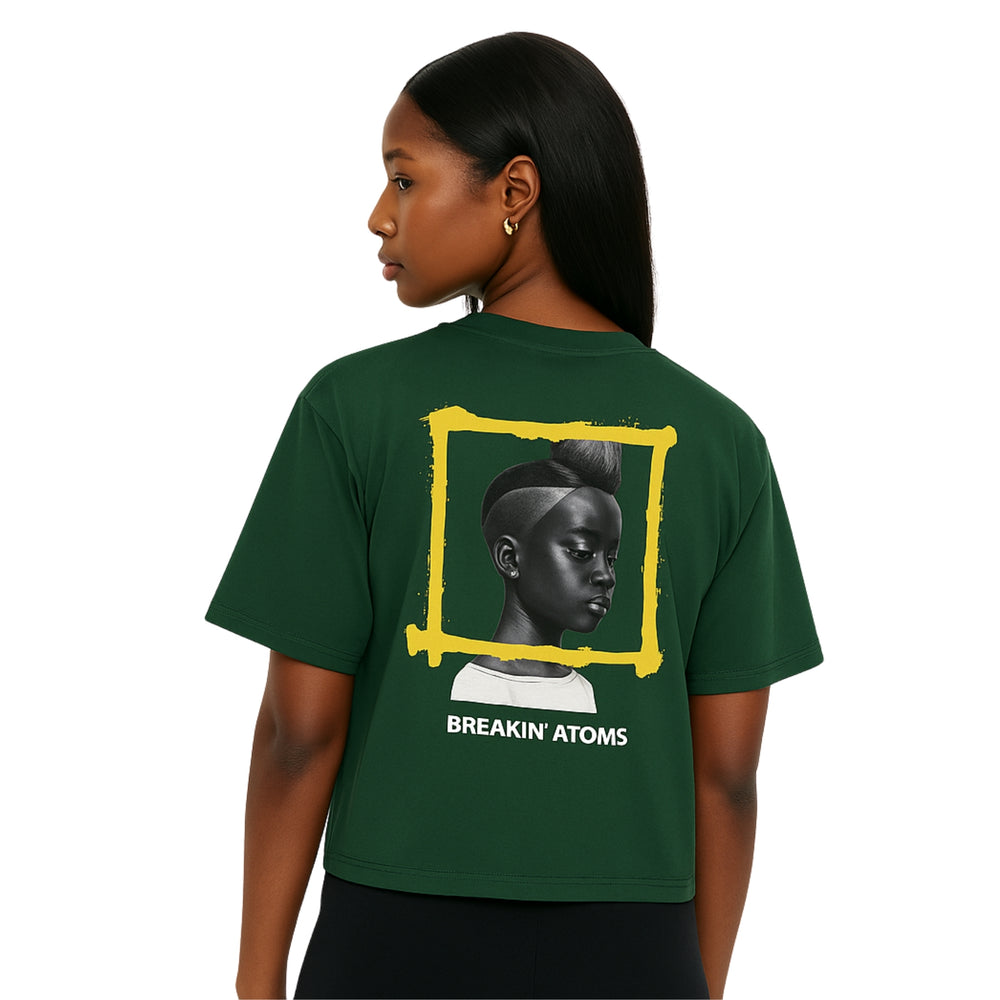 Model wearing Breakin' Atoms Indelible Mark Collection: "In Her Eyes" tee in sports dark green, featuring a stunning grayscale portrait of a woman framed in bold yellow brushstrokes — a tribute to heritage, identity, and unspoken strength. — Breakin Atoms premium streetwear