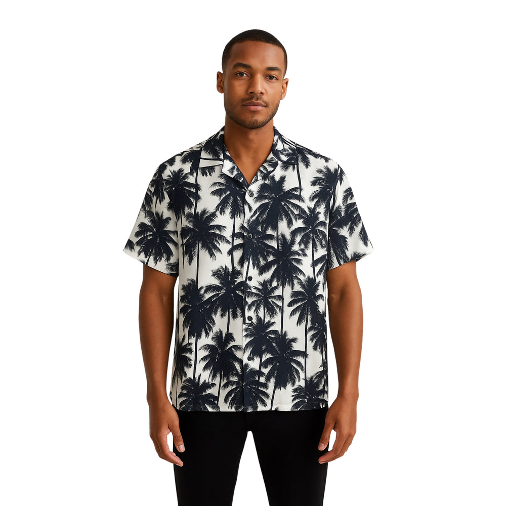 Model wearing Breakin' Atoms "Monochrome Palm Shadow Button-Up," a short sleeve tropical shirt with all-over black palm tree silhouettes on a white background — perfect for vacation or summer streetwear. — Breakin Atoms premium streetwear