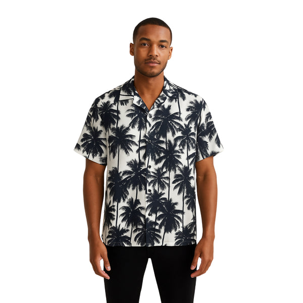Model wearing Breakin' Atoms "Monochrome Palm Shadow Button-Up," a short sleeve tropical shirt with all-over black palm tree silhouettes on a white background — perfect for vacation or summer streetwear.