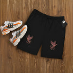 Lifestyle photo of black Breakin’ Atoms Twin Flam Shorts with red phoenix DTF print, styled with white sneakers. thumbnail 8