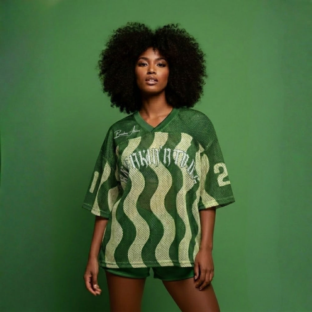  Full-length view of a model wearing the Breakin’ Atoms WaveFront 21 green mesh V-neck jersey with cream wave pattern, oversized fit, and “21” sleeve numbering. — Breakin Atoms premium streetwear