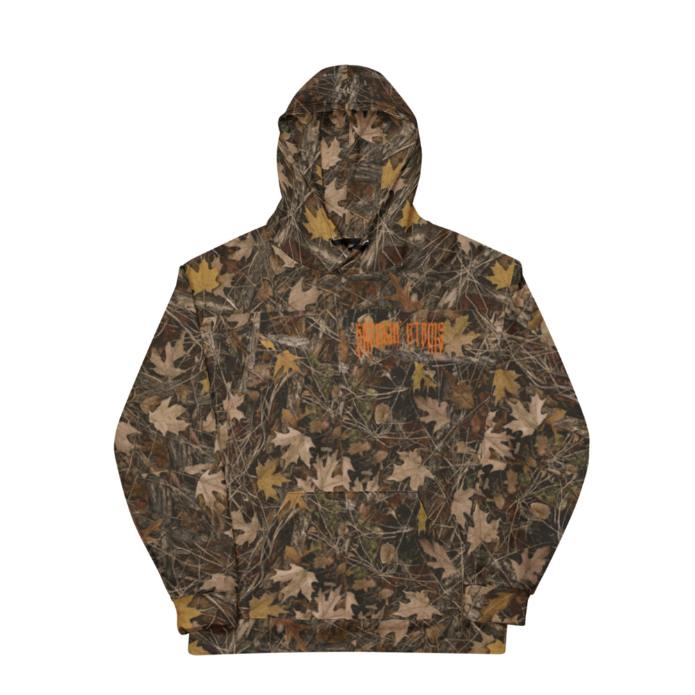Front view of a Breakin’ Atoms camouflage hoodie in a fall leaf pattern with brown, tan, and olive tones. The hoodie features a kangaroo pocket and an orange gothic-style Breakin’ Atoms logo printed on the left chest. — Breakin Atoms premium streetwear